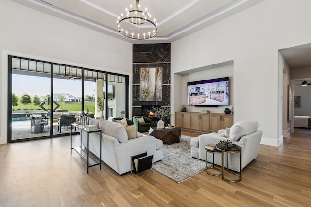 1644 Aster Way, Celina, TX 75009 - living room featuring a towering ceiling, a chandelier, wood finished floors, a fireplace, and baseboards