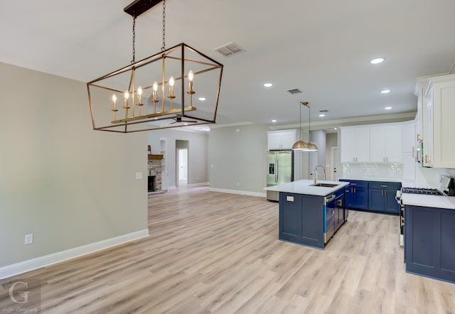 kitchen with a center island with sink, hanging light fixtures, sink, white cabinetry, and blue cabinets