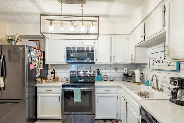 kitchen featuring white cabinets, appliances with stainless steel finishes, tasteful backsplash, and sink