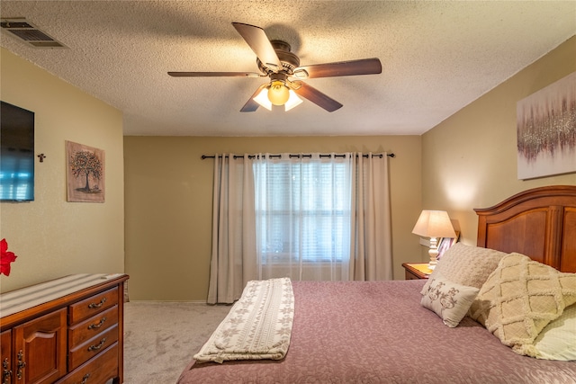 carpeted bedroom with ceiling fan and a textured ceiling