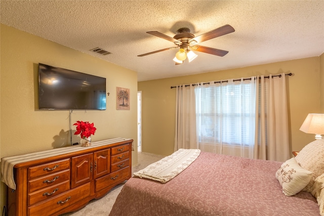 carpeted bedroom featuring ceiling fan and a textured ceiling