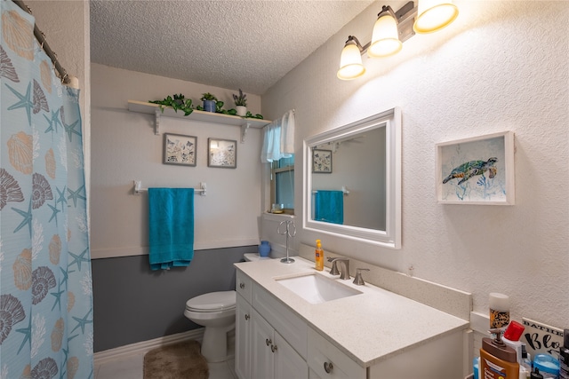 bathroom with a textured ceiling, vanity, and toilet