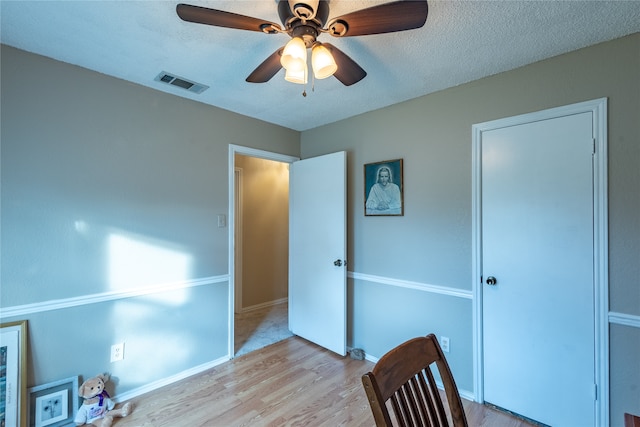 bedroom featuring light hardwood / wood-style flooring, ceiling fan, and a textured ceiling