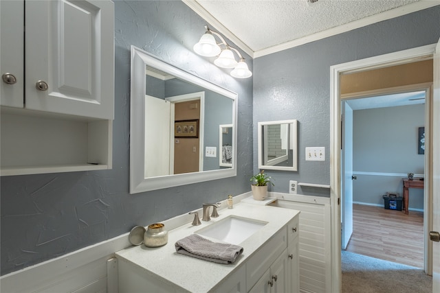 bathroom with vanity, a textured ceiling, hardwood / wood-style floors, and ornamental molding