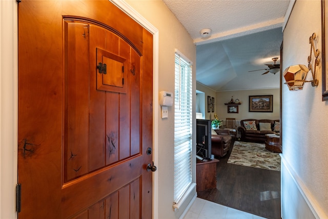 foyer entrance featuring ceiling fan, a textured ceiling, lofted ceiling, and light hardwood / wood-style floors