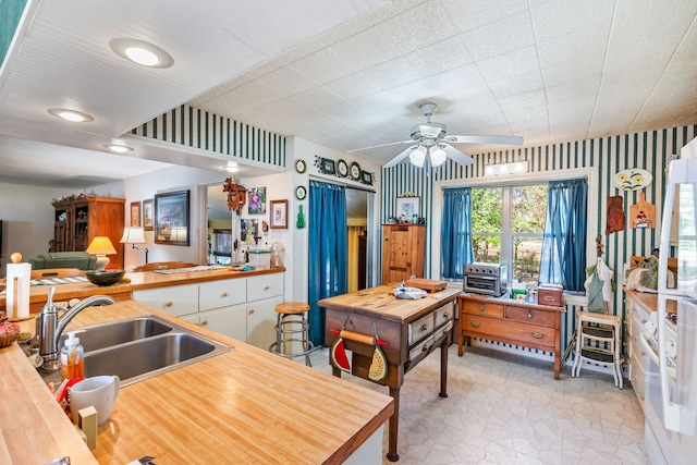 kitchen featuring kitchen peninsula, ceiling fan, and sink