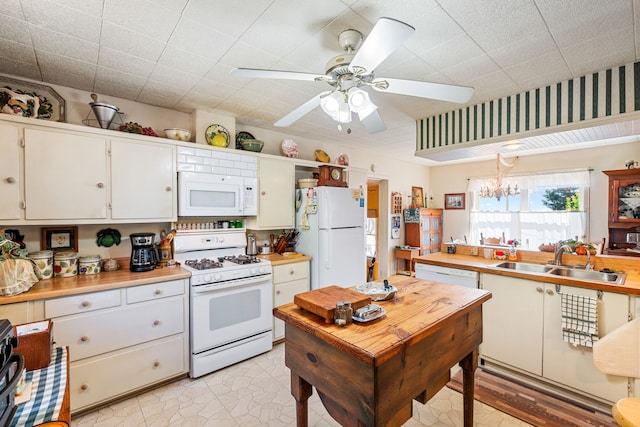 kitchen with ceiling fan with notable chandelier, white appliances, white cabinetry, and sink