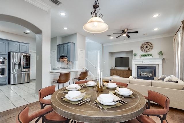 kitchen featuring crown molding, light wood-type flooring, stainless steel refrigerator with ice dispenser, and a tile fireplace