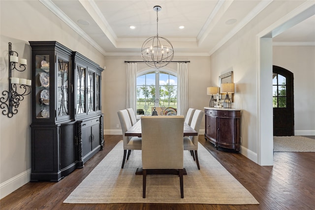 dining space with an inviting chandelier, crown molding, dark hardwood / wood-style floors, and a raised ceiling