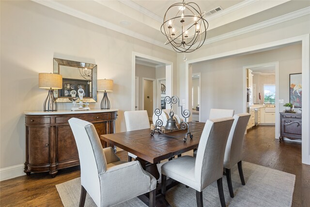 dining room with a notable chandelier, a tray ceiling, ornamental molding, and dark hardwood / wood-style flooring