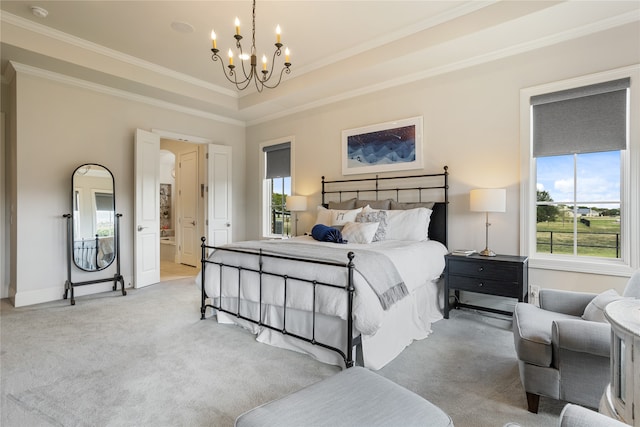 carpeted bedroom featuring ornamental molding, an inviting chandelier, a tray ceiling, and ensuite bath