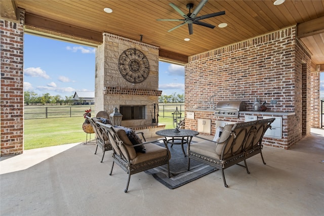 view of patio / terrace featuring area for grilling, an outdoor stone fireplace, and ceiling fan