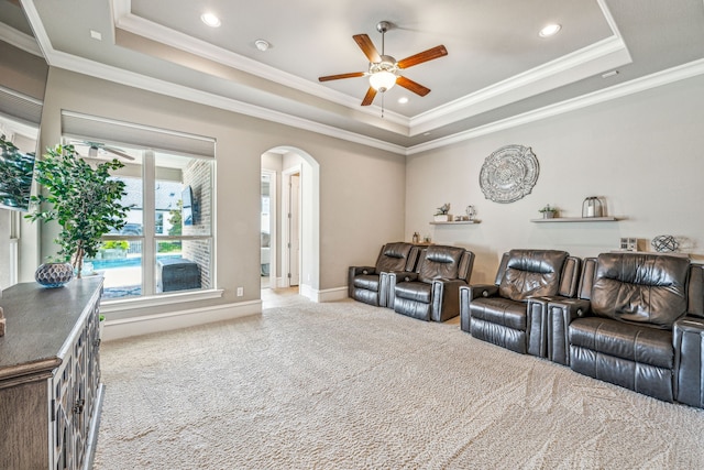 home theater featuring carpet flooring, a raised ceiling, ceiling fan, and ornamental molding