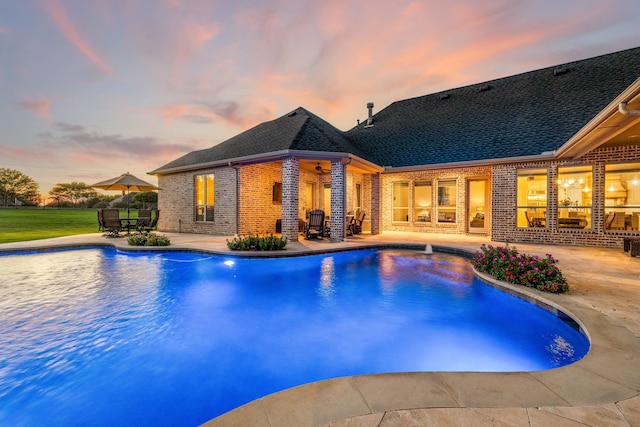 pool at dusk featuring a patio area