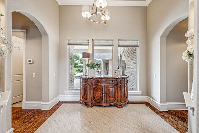 entryway with crown molding, hardwood / wood-style floors, and a chandelier