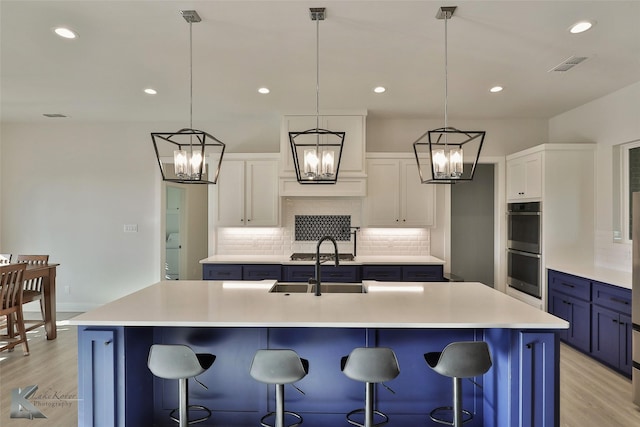 kitchen featuring white cabinetry, a large island, a breakfast bar, and pendant lighting