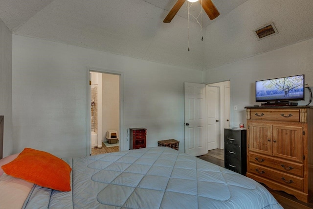 bedroom featuring lofted ceiling, connected bathroom, dark wood-type flooring, and ceiling fan