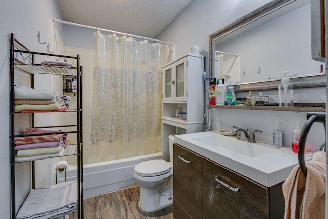 full bathroom with shower / bath combo, a textured ceiling, hardwood / wood-style flooring, vanity, and toilet