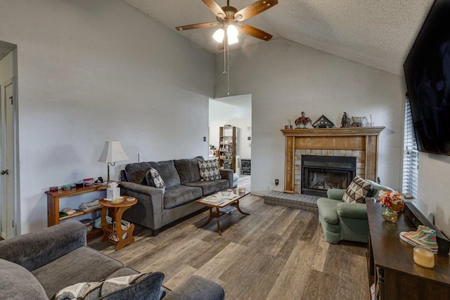 living room with ceiling fan, a textured ceiling, hardwood / wood-style floors, and vaulted ceiling