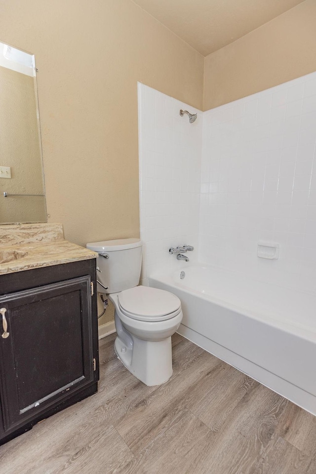 full bathroom featuring washtub / shower combination, vanity, hardwood / wood-style flooring, and toilet