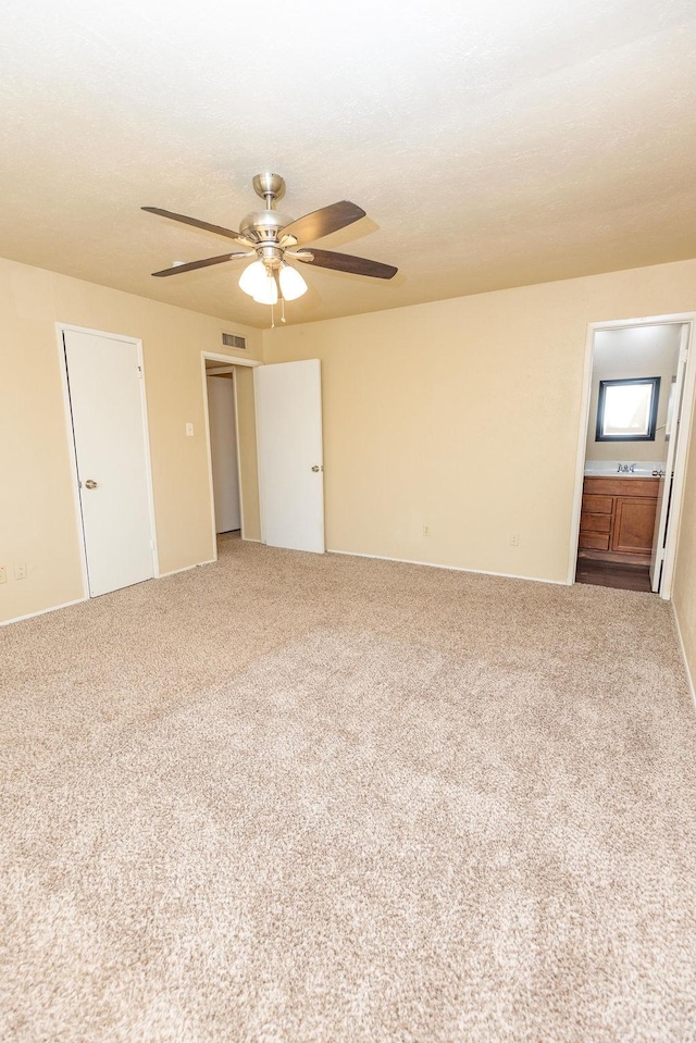 unfurnished bedroom with carpet, ceiling fan, and connected bathroom