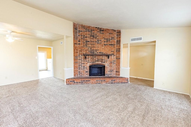 unfurnished living room with ceiling fan, carpet floors, lofted ceiling, and a brick fireplace