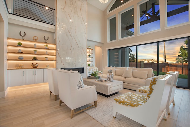 living room featuring a premium fireplace, light hardwood / wood-style floors, and high vaulted ceiling