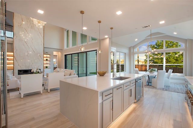 kitchen with a high end fireplace, dishwasher, sink, an island with sink, and white cabinetry