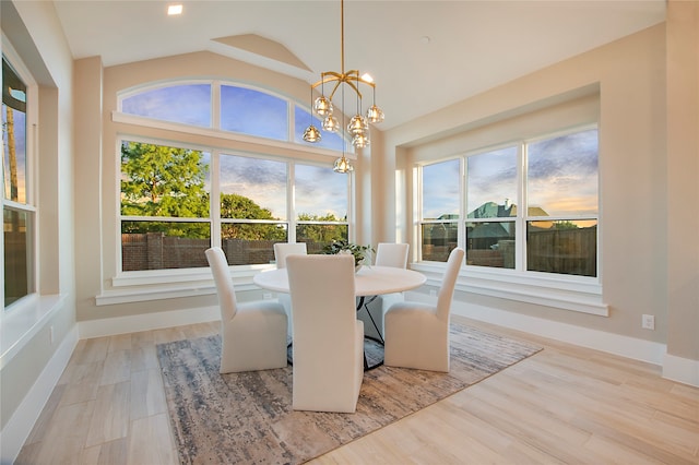 dining space with lofted ceiling, an inviting chandelier, and light hardwood / wood-style flooring