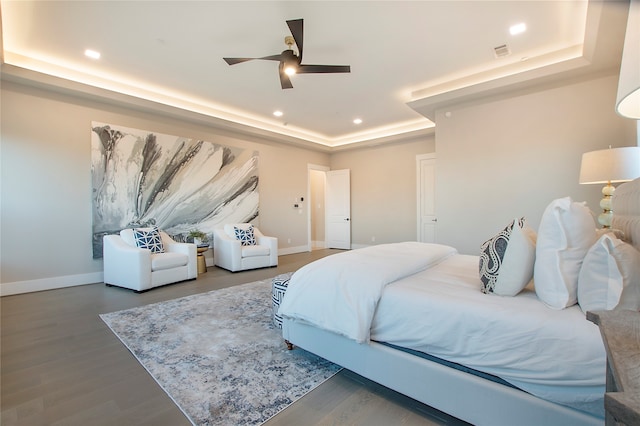 bedroom with a tray ceiling, ceiling fan, and hardwood / wood-style flooring