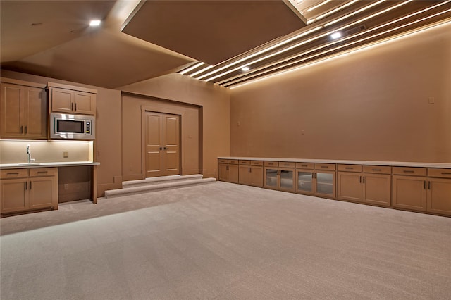 interior space with light carpet, stainless steel microwave, and sink