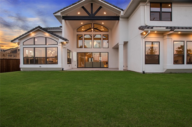 back house at dusk featuring french doors and a lawn