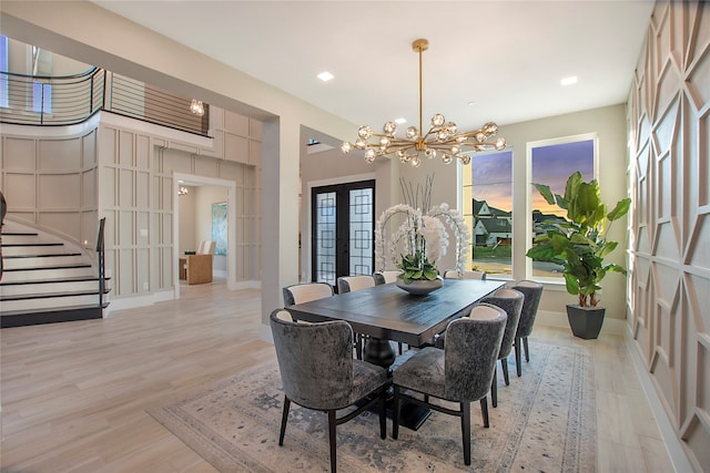 dining space with a chandelier, french doors, and light hardwood / wood-style flooring