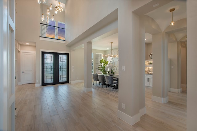 entrance foyer with a notable chandelier, light hardwood / wood-style floors, and a high ceiling