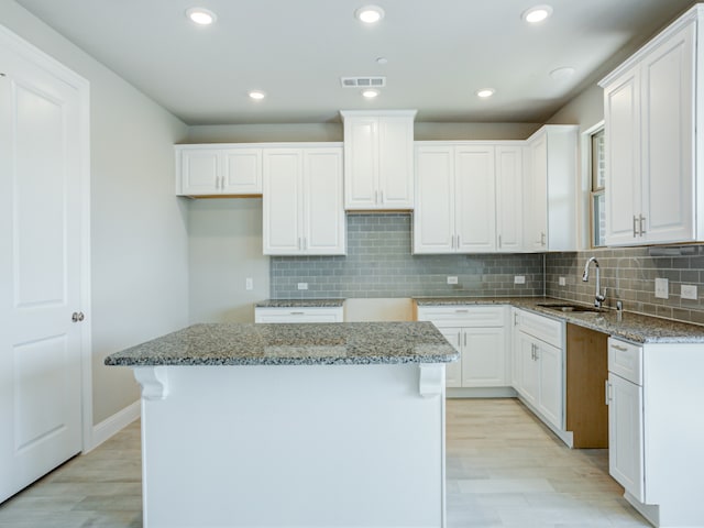 kitchen featuring a kitchen island, light hardwood / wood-style floors, sink, and white cabinetry