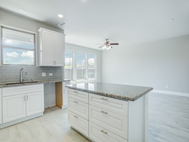 kitchen featuring light stone countertops, sink, ceiling fan, and white cabinets