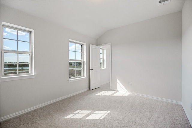 spare room with vaulted ceiling and light carpet