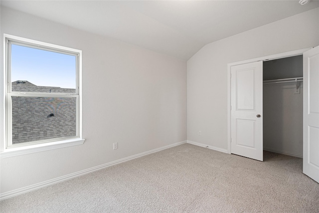 unfurnished bedroom with light colored carpet, vaulted ceiling, and a closet