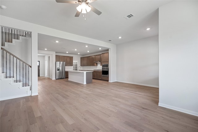 kitchen with sink, light hardwood / wood-style flooring, ceiling fan, stainless steel appliances, and a kitchen island with sink