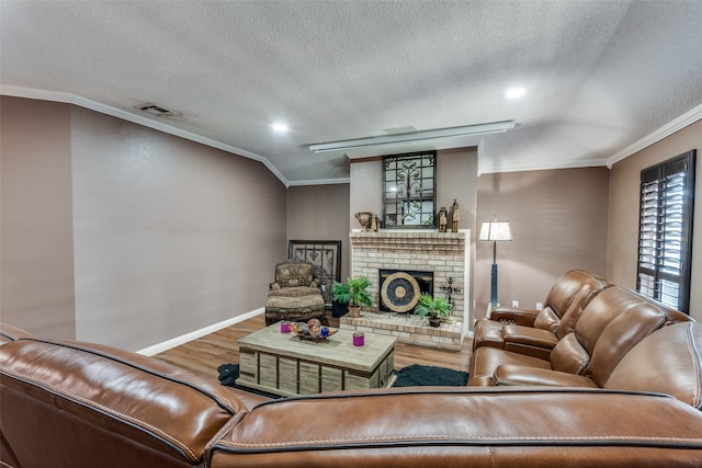 living room featuring wood-type flooring, a textured ceiling, a brick fireplace, and ornamental molding