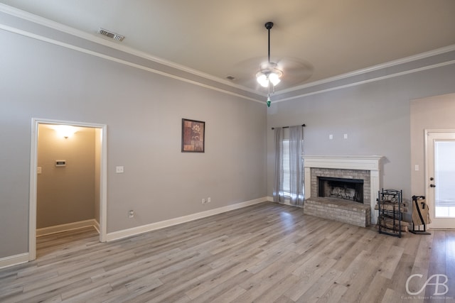 unfurnished living room with crown molding, light hardwood / wood-style floors, ceiling fan, and a brick fireplace