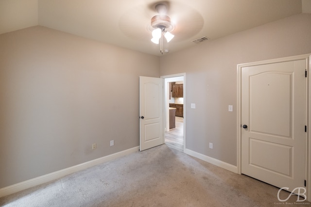 unfurnished bedroom featuring lofted ceiling, light carpet, and ceiling fan