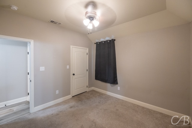 empty room with lofted ceiling, ceiling fan, and light colored carpet