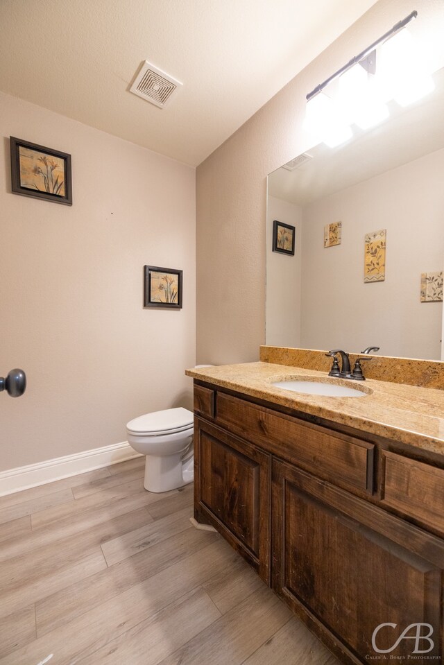 bathroom with hardwood / wood-style floors, vanity, and toilet