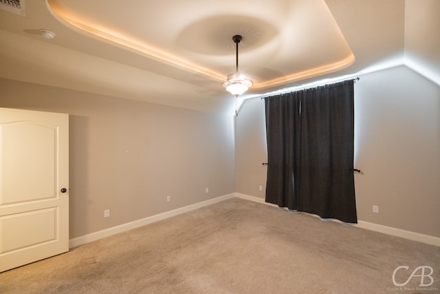 carpeted spare room with a tray ceiling