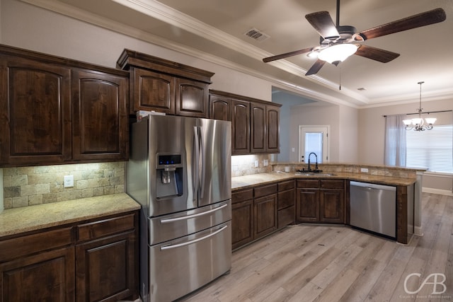 kitchen with appliances with stainless steel finishes, tasteful backsplash, ceiling fan with notable chandelier, light hardwood / wood-style flooring, and sink