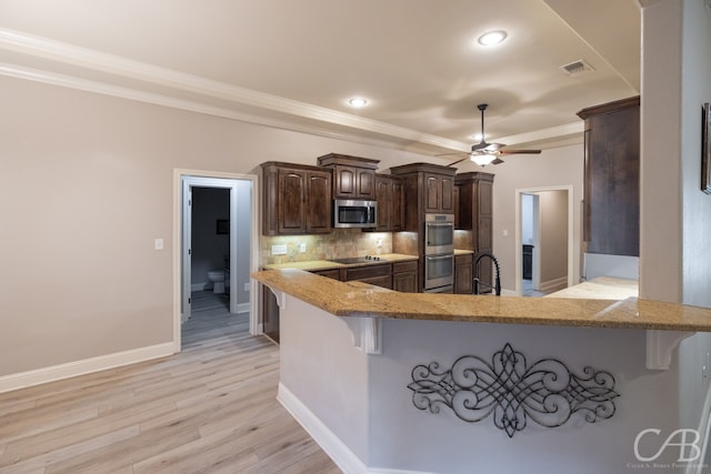 kitchen with ceiling fan, kitchen peninsula, appliances with stainless steel finishes, light wood-type flooring, and a kitchen bar