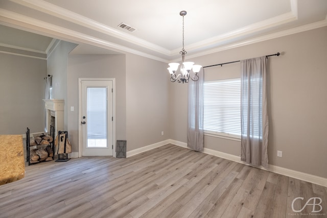 spare room with a wealth of natural light, a chandelier, and light hardwood / wood-style floors