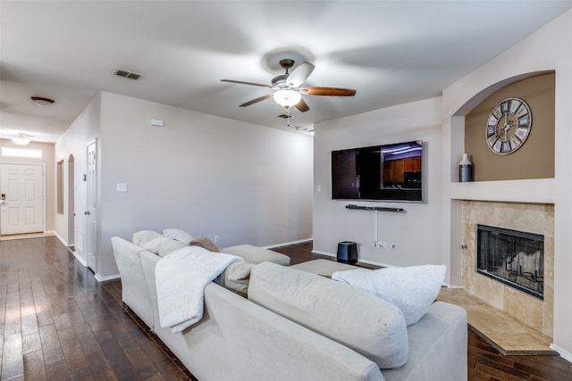 living room with ceiling fan, a fireplace, and dark wood-type flooring