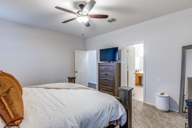 bedroom with ceiling fan, ensuite bath, and light carpet